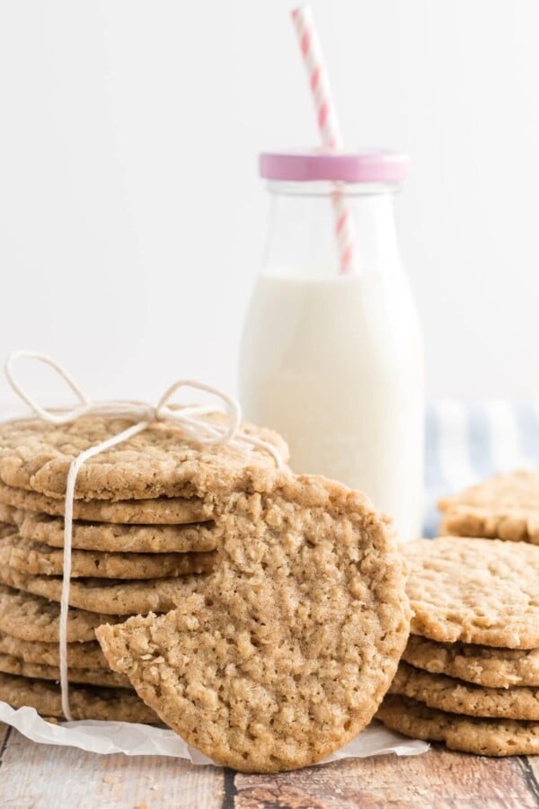 oatmeal cookies tied up with twine, with a bottle of milk in the background and a pink striped straw