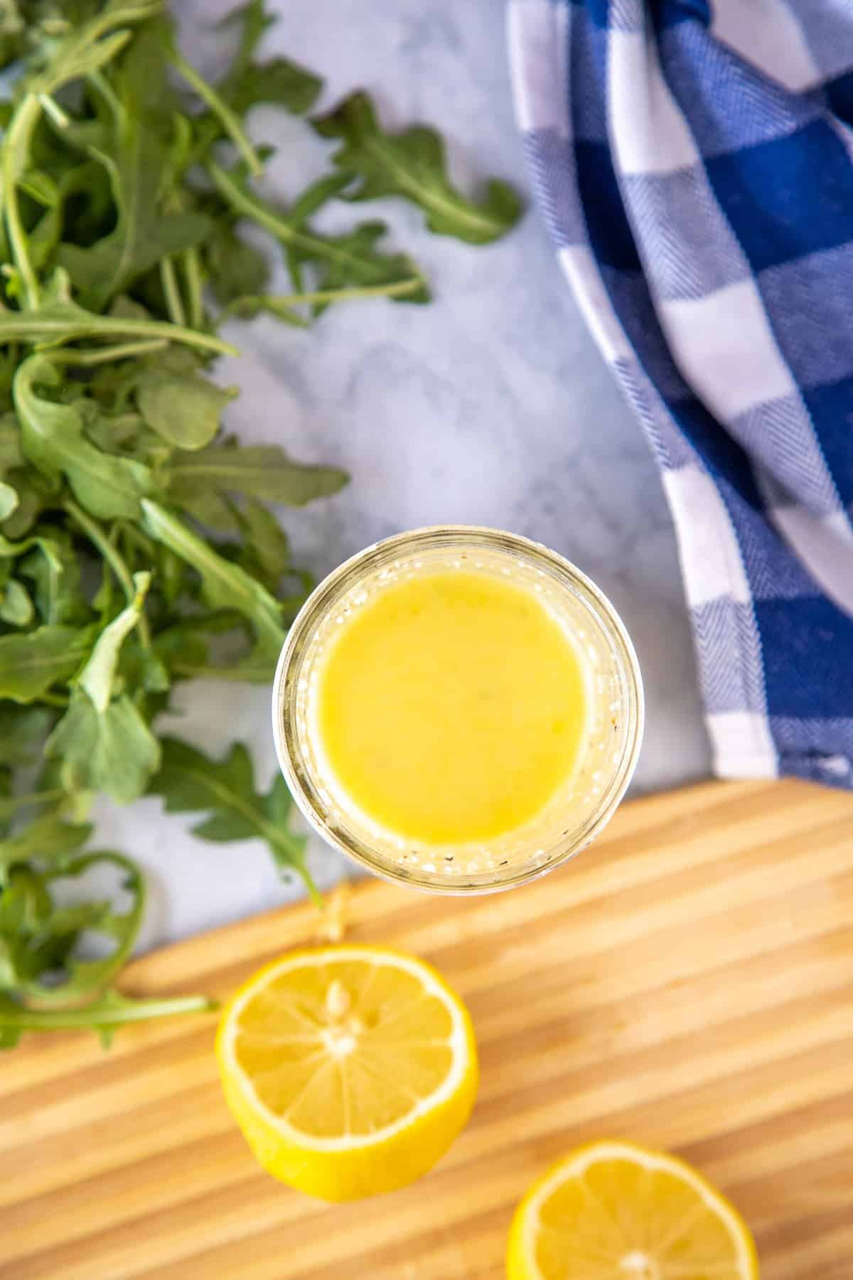 lemon vinaigrette in a glass jar with cut lemons