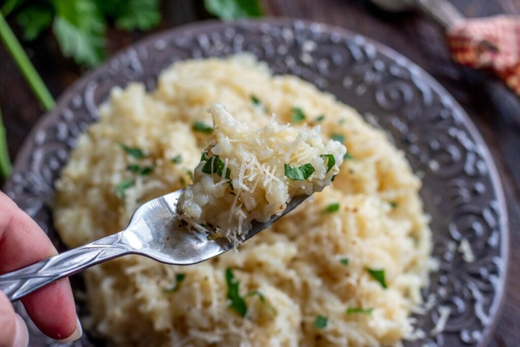 a fork full of risotto on a grey plate