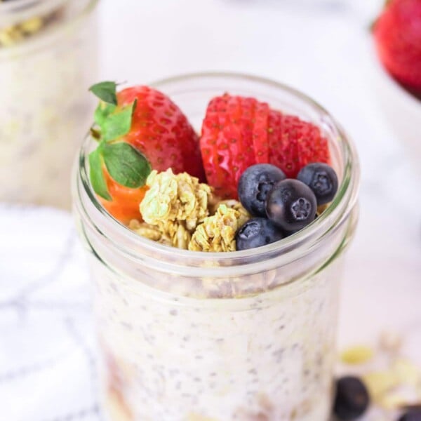overnight oats with granola and berries on a marble backdrop