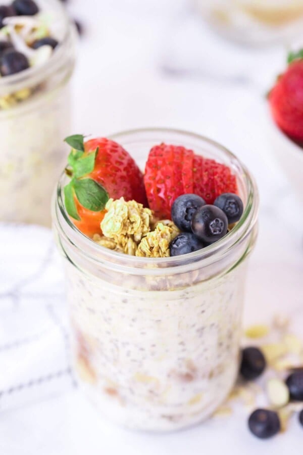 overnight oats with granola and berries on a marble backdrop