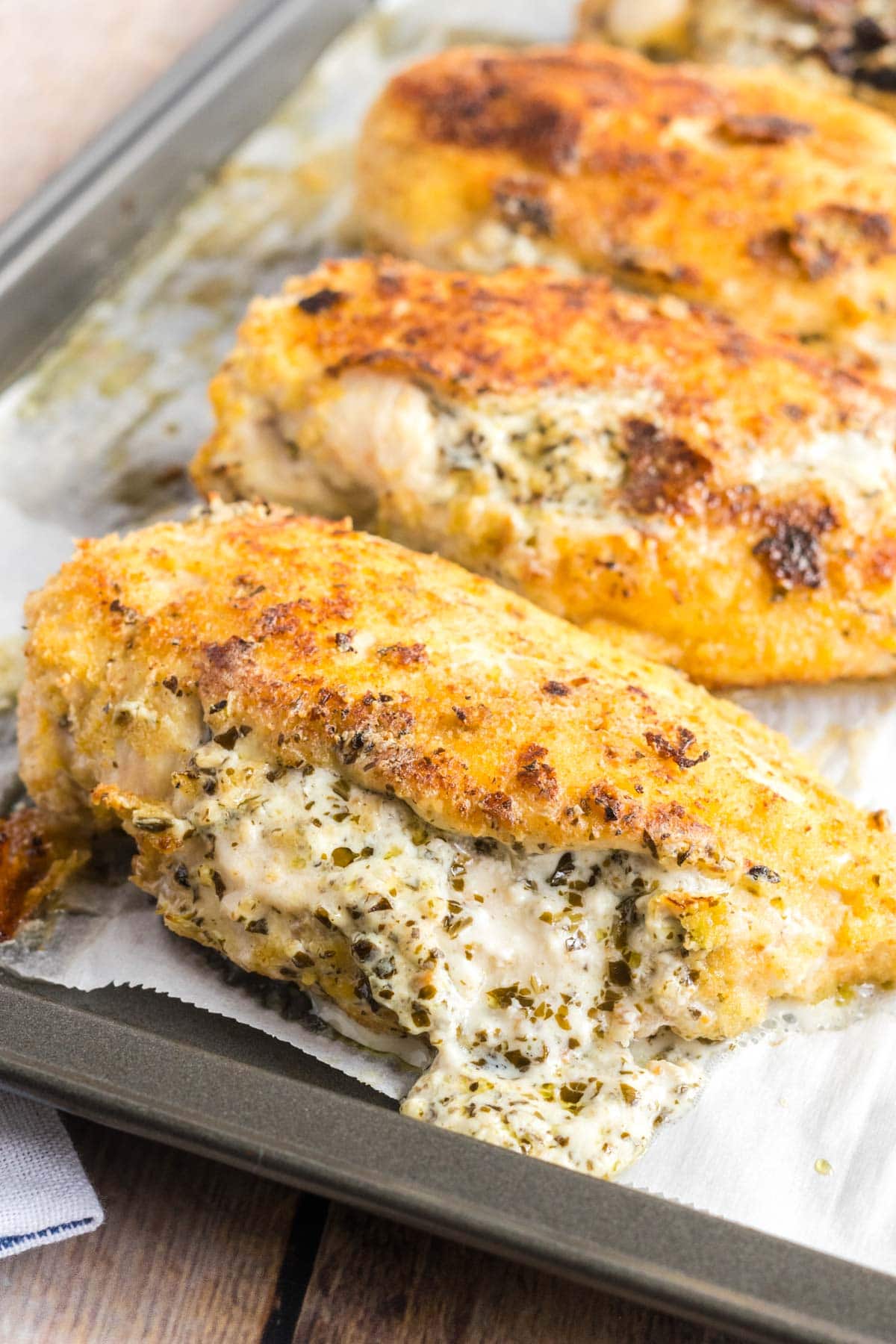 chicken breasts on a baking sheet with filling oozing out