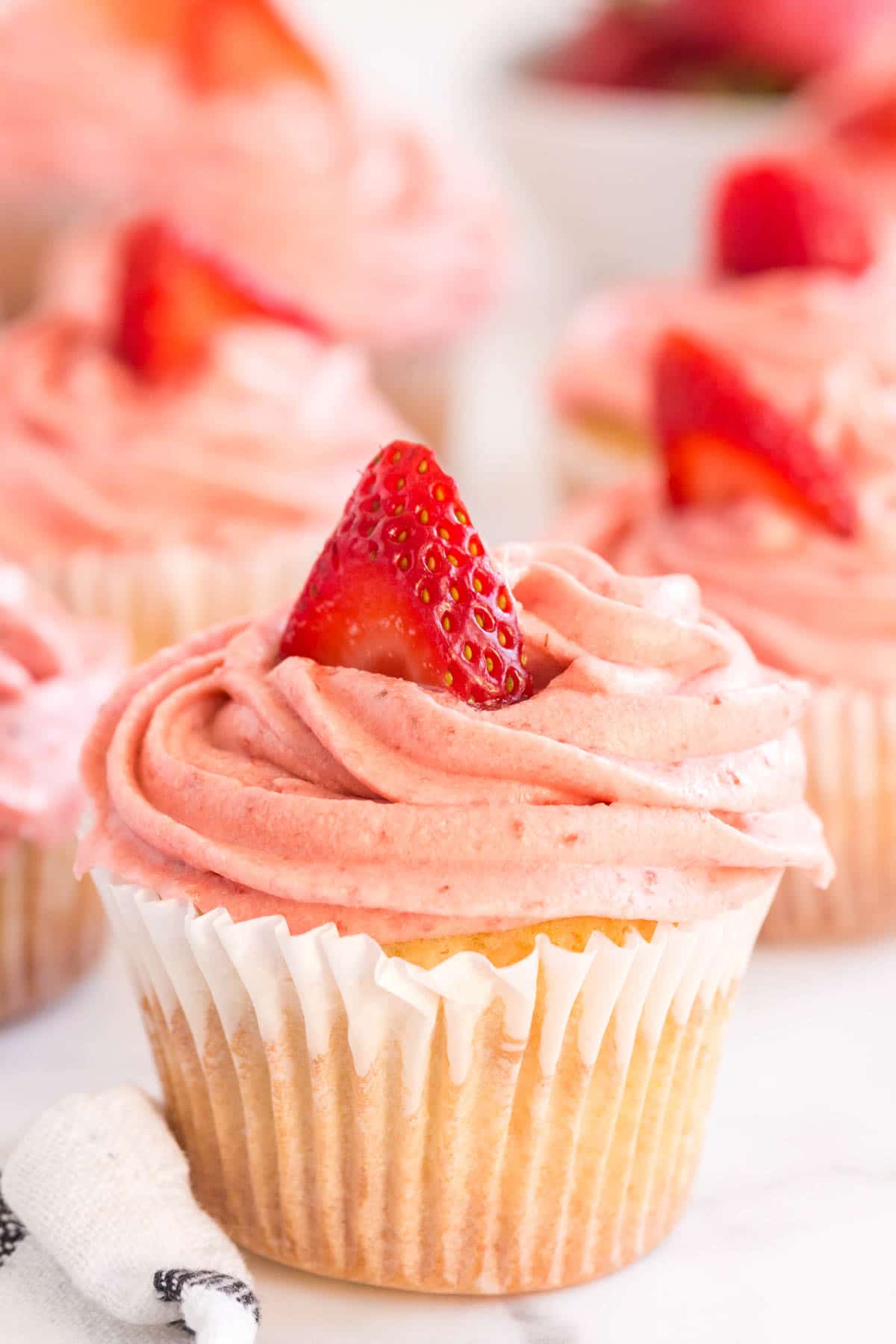 vanilla cupcake with pink frosting and a strawberry