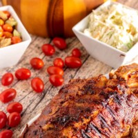 grilled ribs on a white plate with salads around
