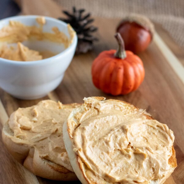 wooden board with a bagel schmeared with pumpkin cream cheese