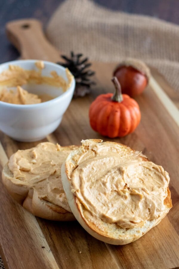 wooden board with a bagel schmeared with pumpkin cream cheese