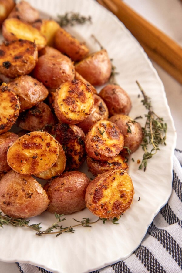 roasted baby potatoes on a white platter with a striped napkin