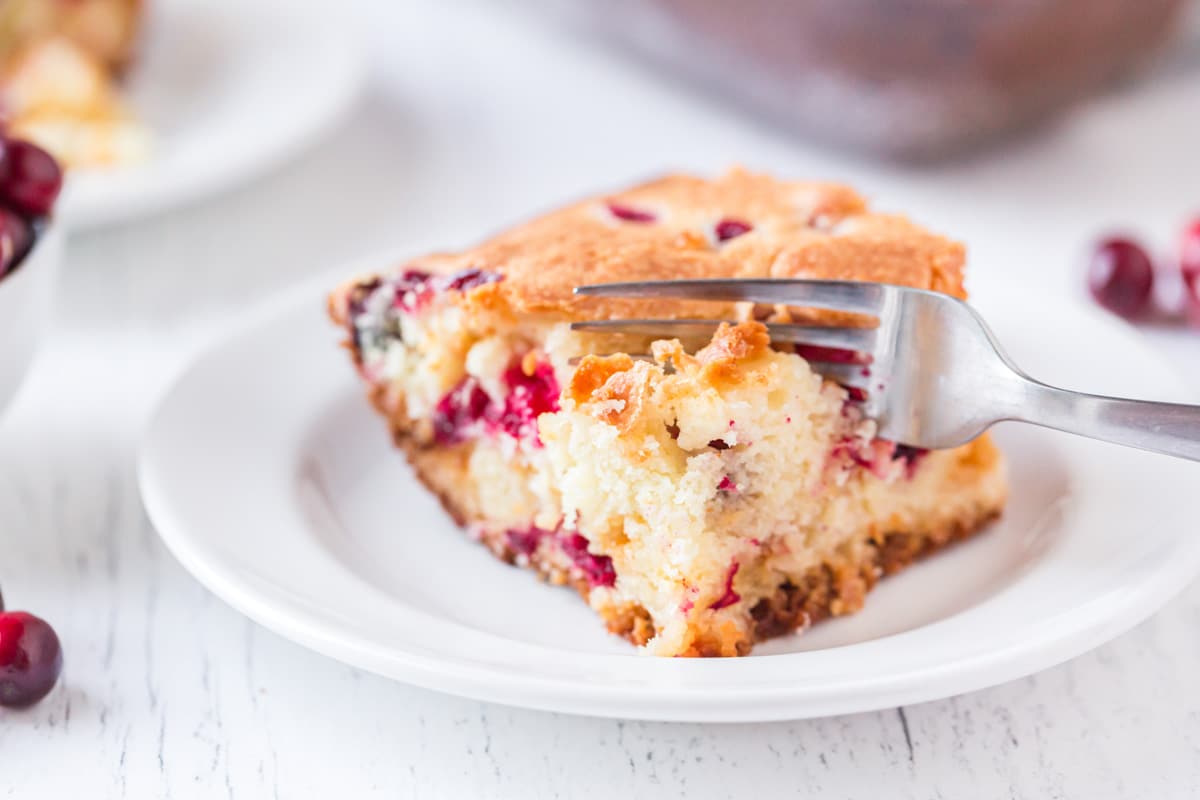 cranberry cake on a white plate with a fork