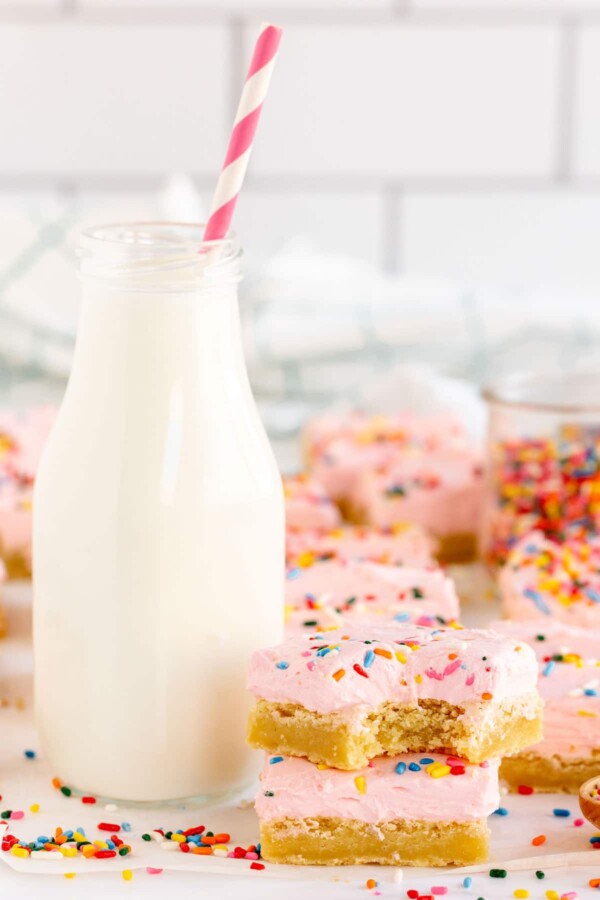 sugar cookie bars with pink frosting and milk