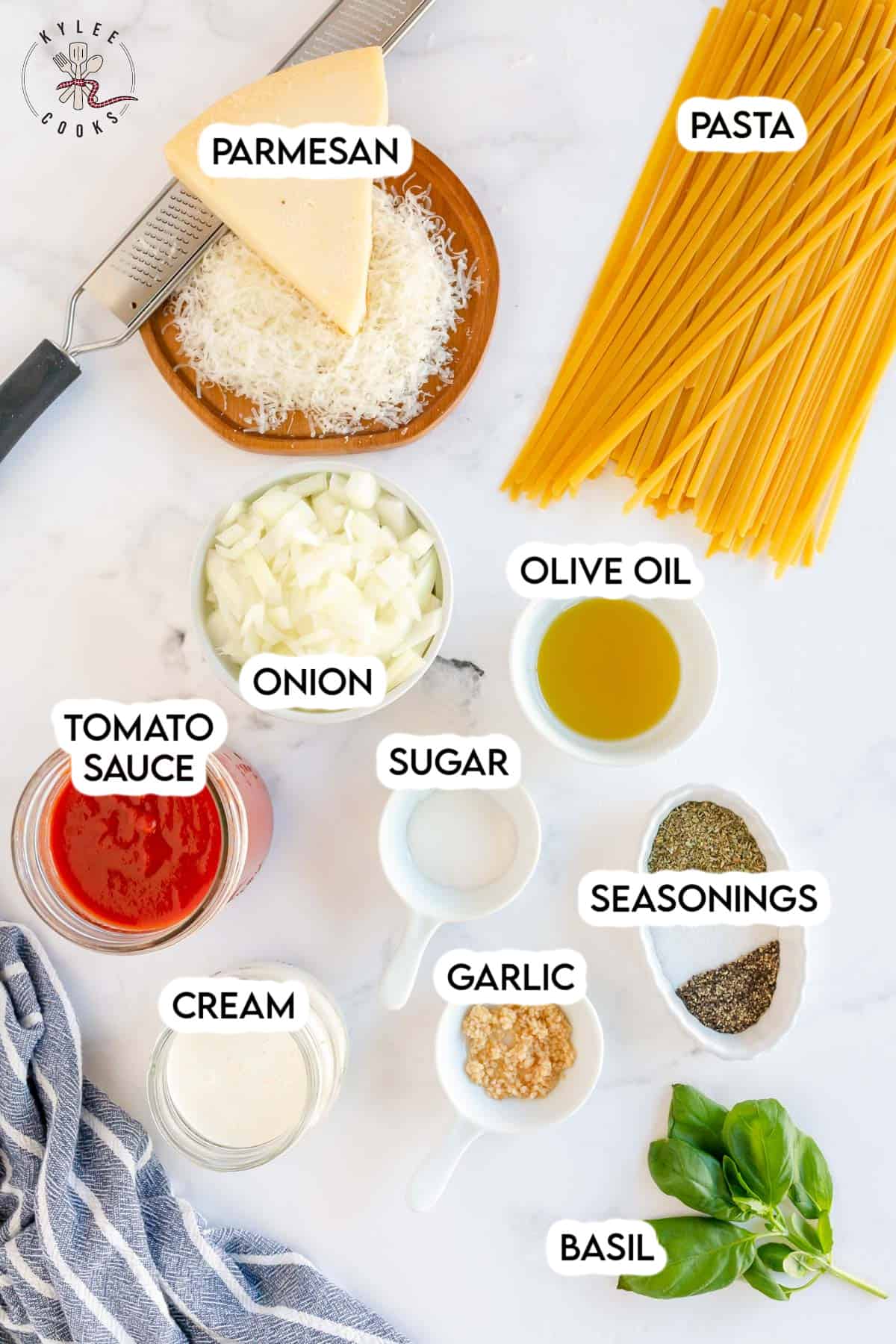 ingredients to make tomato cream sauce laid out on a board and labeled