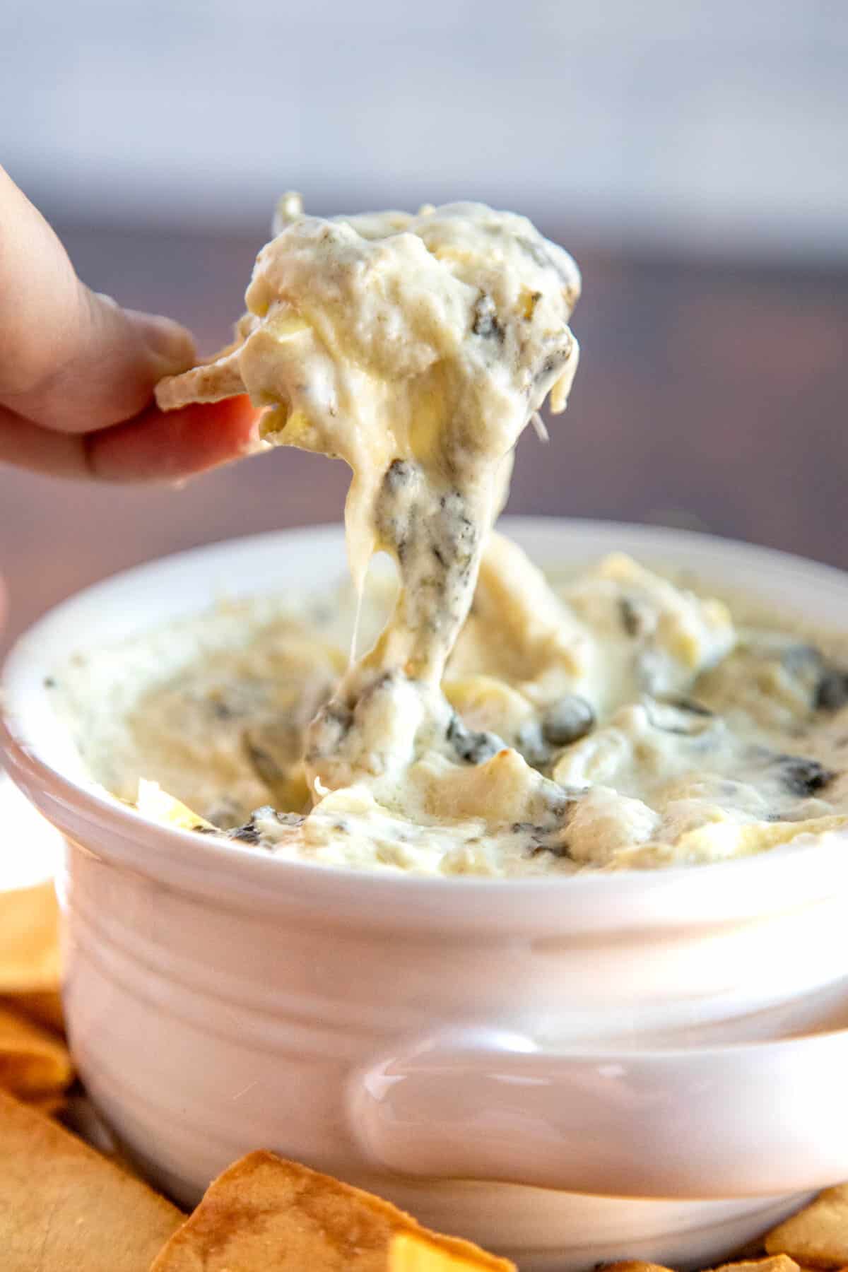 spinach artichoke dip being pulled from a bowl with garlic bread with text overlay