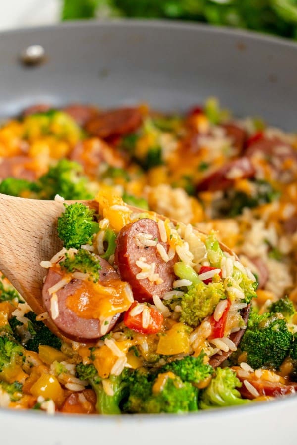 sausage and rice with vegetables on a wooden spoon.
