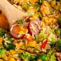 sausage and rice with vegetables on a wooden spoon.
