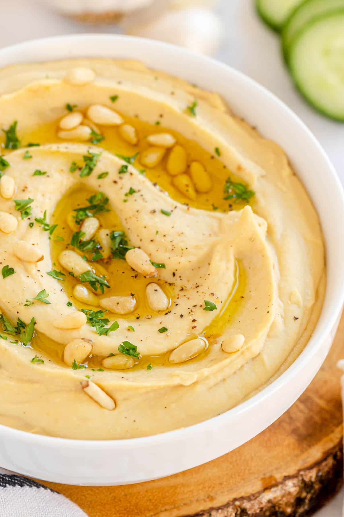 roasted garlic hummus in a white bowl with pine nuts