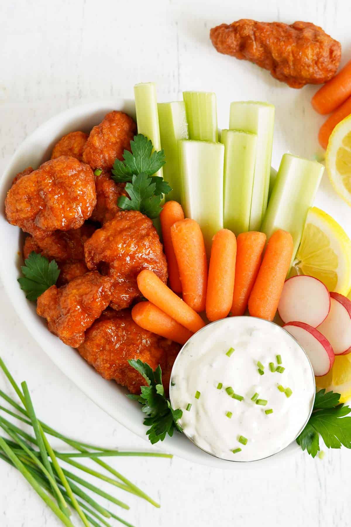 blue cheese dip on a platter with fresh veggies and buffalo chicken.