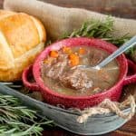 Beef stew in a red bowl with bread