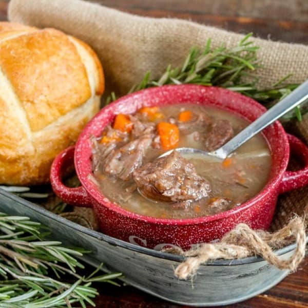 Beef stew in a red bowl with bread