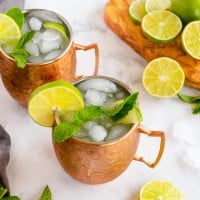 2 moscow mules in copper mugs with mint and limes.