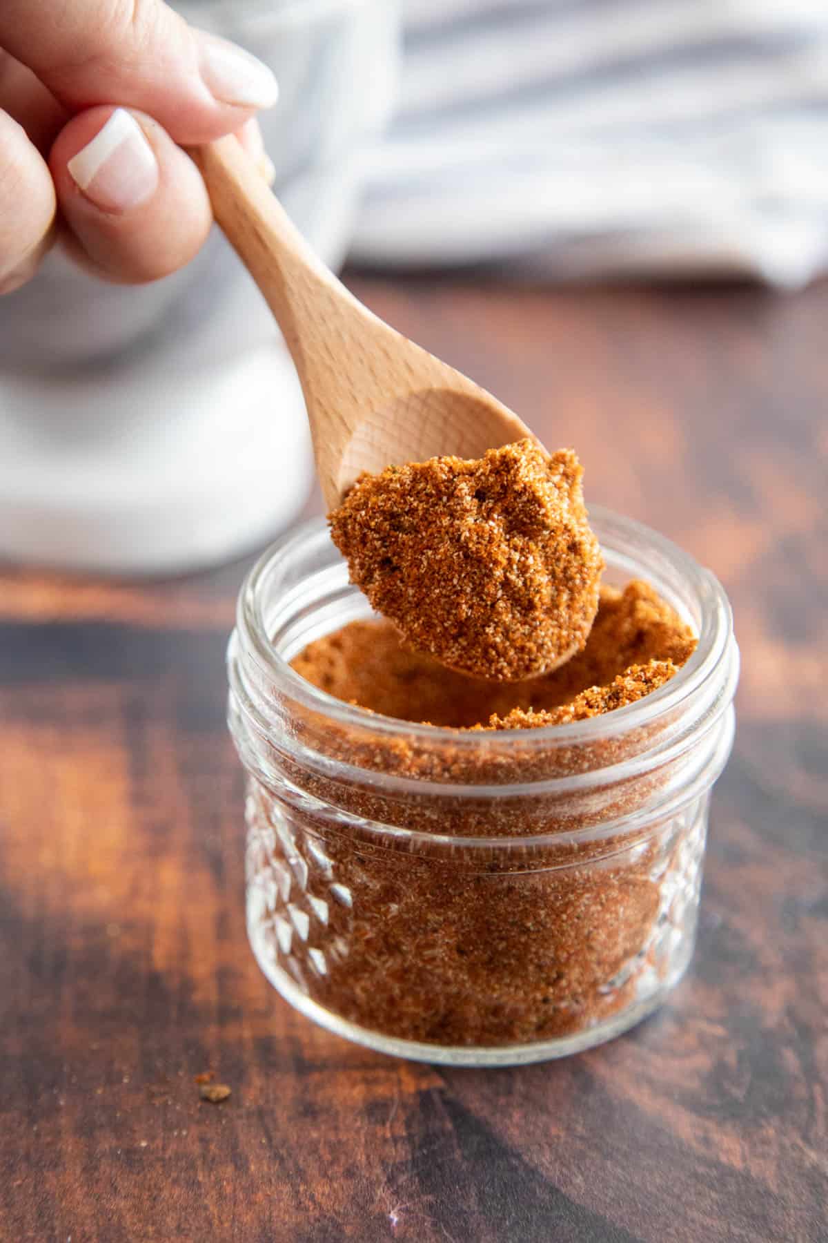 chili powder in a glass jar with a wooden spoon