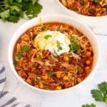 bowl of chicken chili with sour cream, cheese and cilantro on top