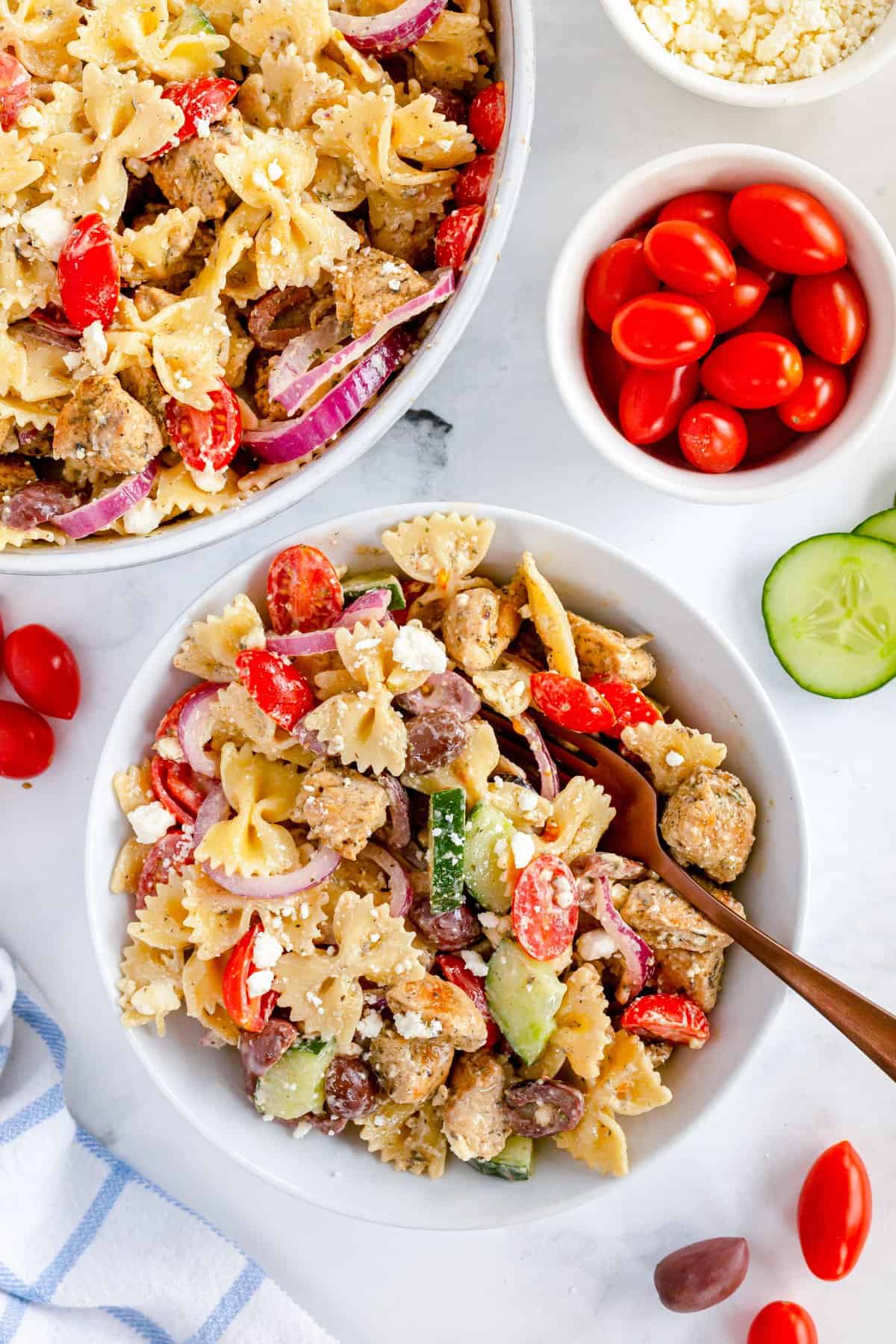 greek pasta salad with serving spoon and veggies