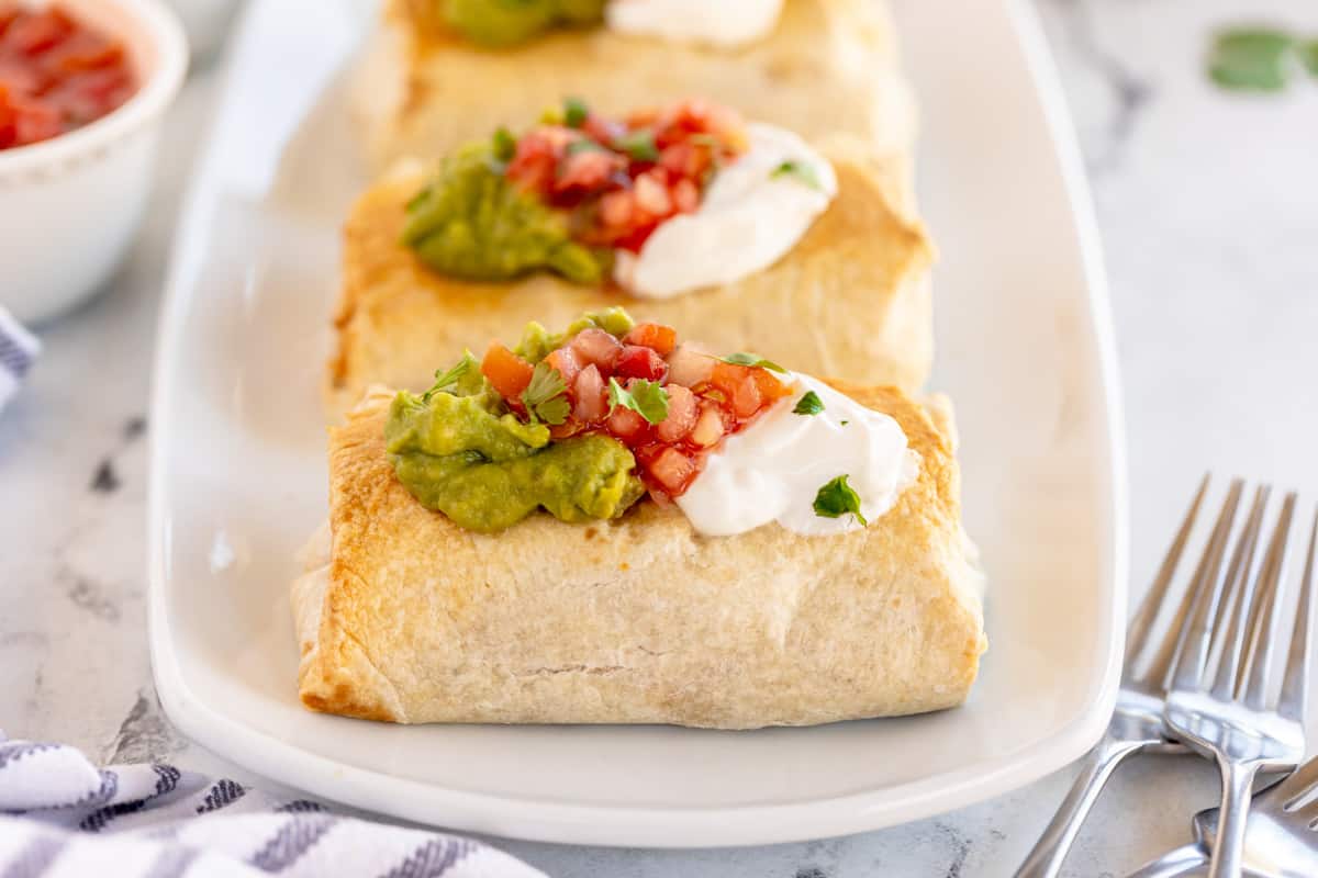 baked chimichangas on a white plate.