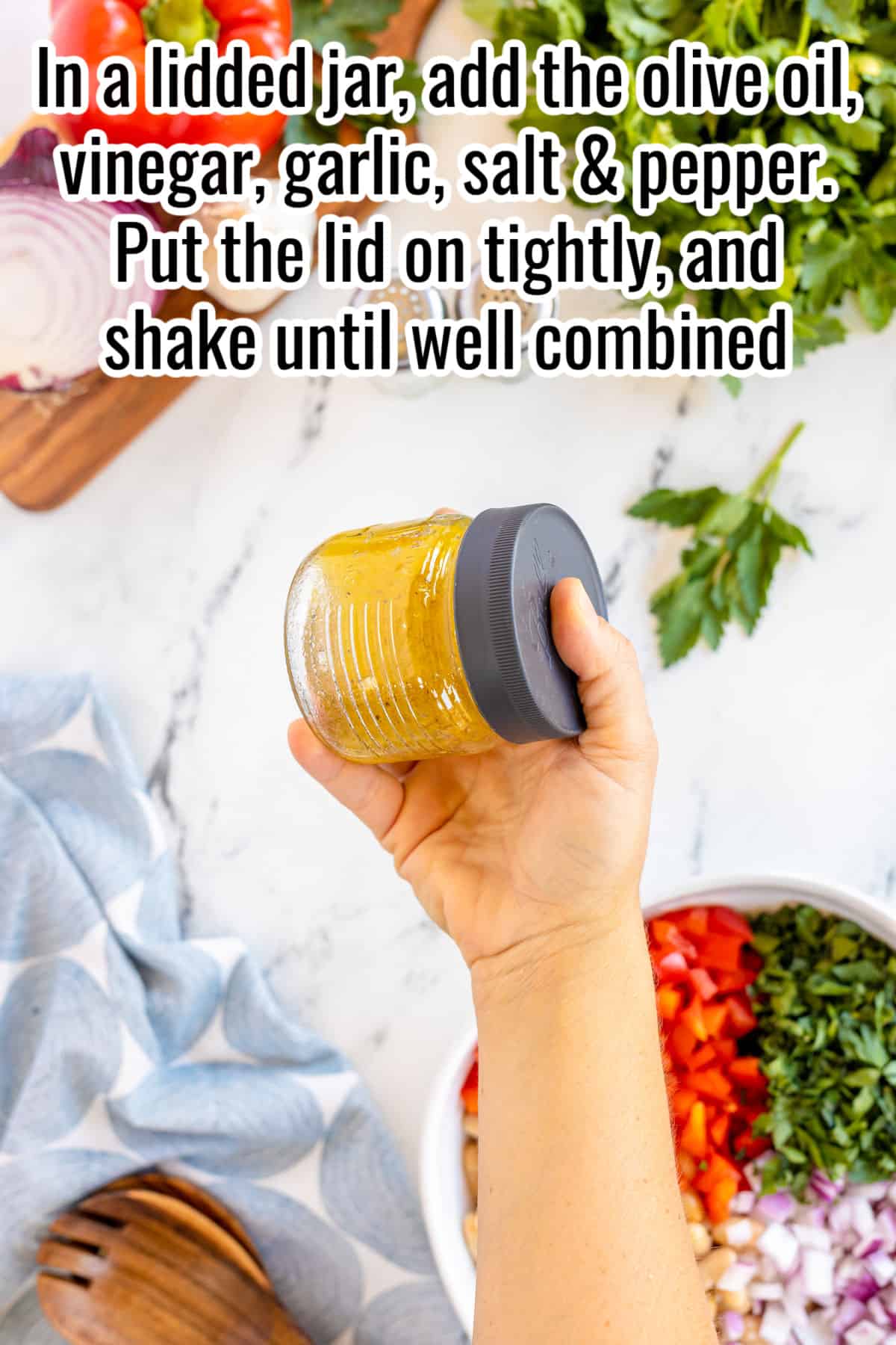 hand holding a jar and shaking up dressing.