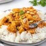 crockpot chicken curry on rice with a fork.