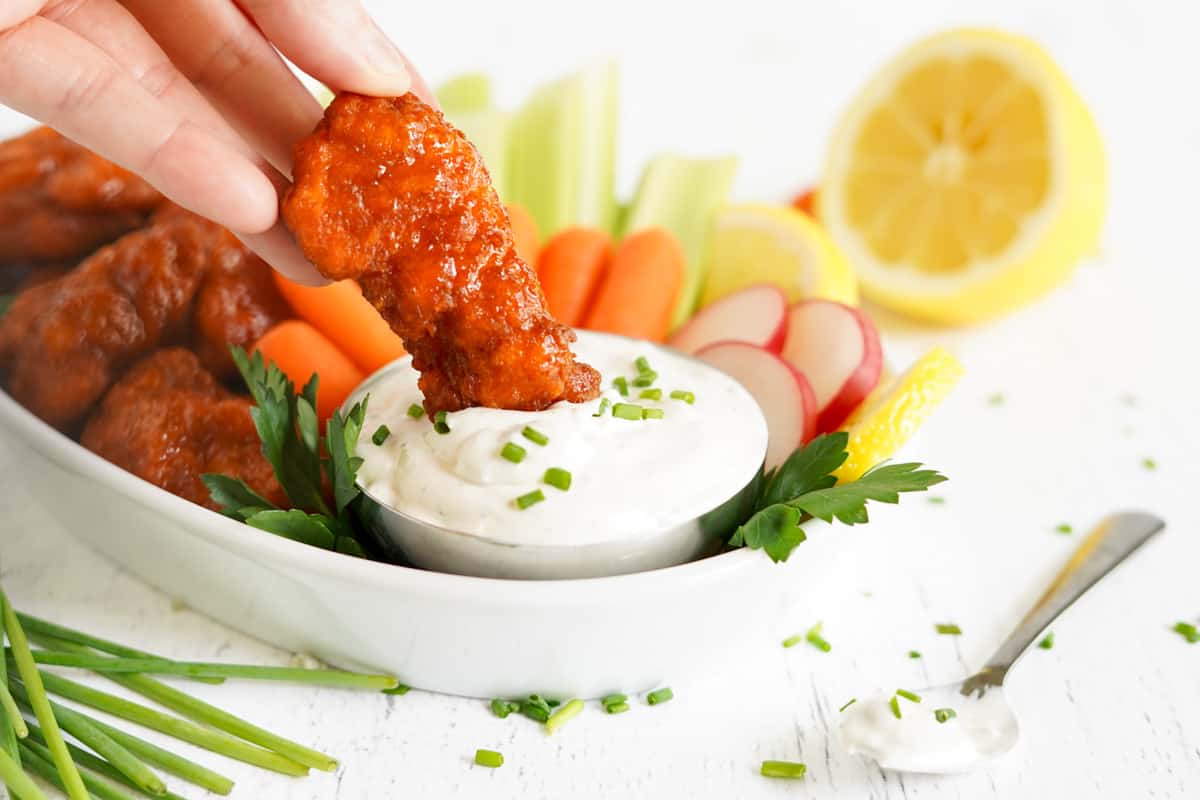 chicken tender being dipped in blue cheese dip.