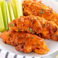 buffalo chicken tenders on a white plate with celery.