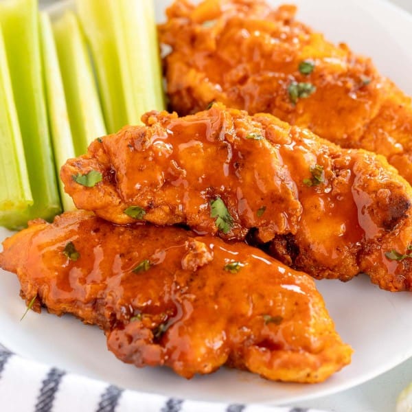 buffalo chicken tenders on a white plate with celery.