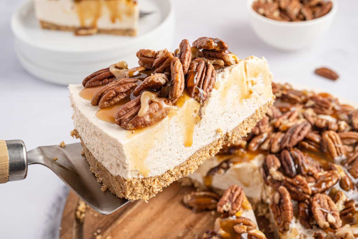 A slice of caramel pecan cheesecake with caramel sauce and pecans on top.