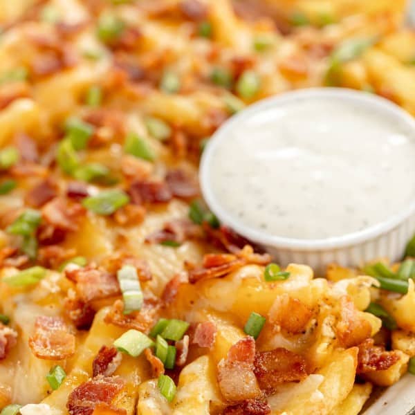 loaded cheese fries on a platter with ranch dip.