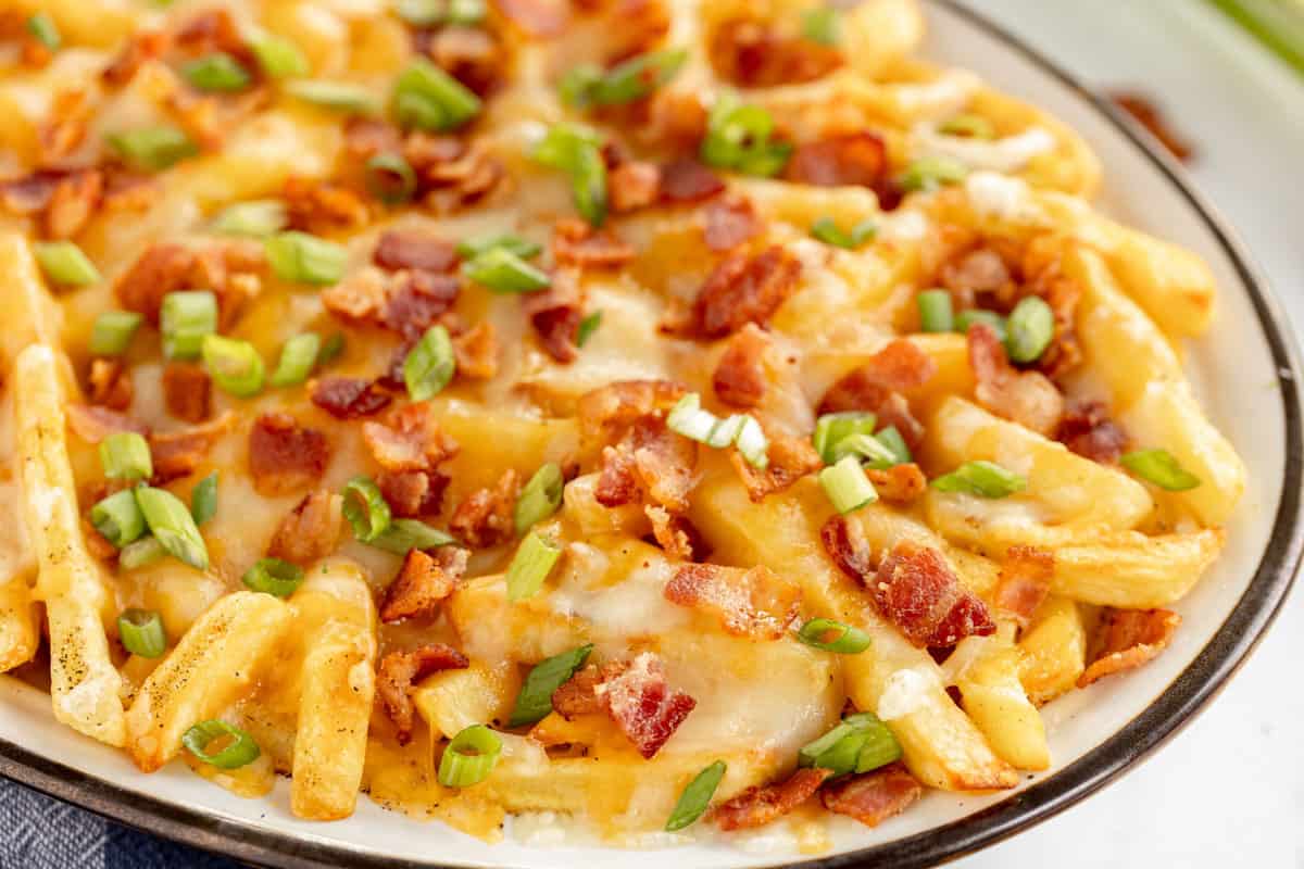 loaded cheese fries on a white platter.