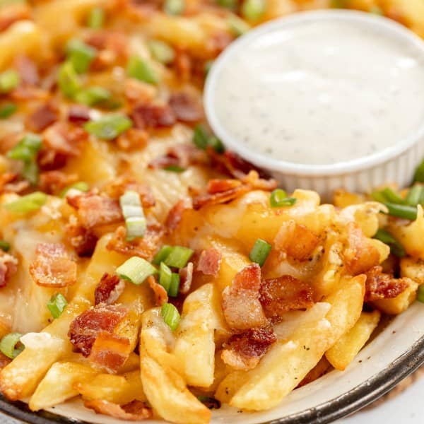 loaded cheese fries on a platter with ranch dip.