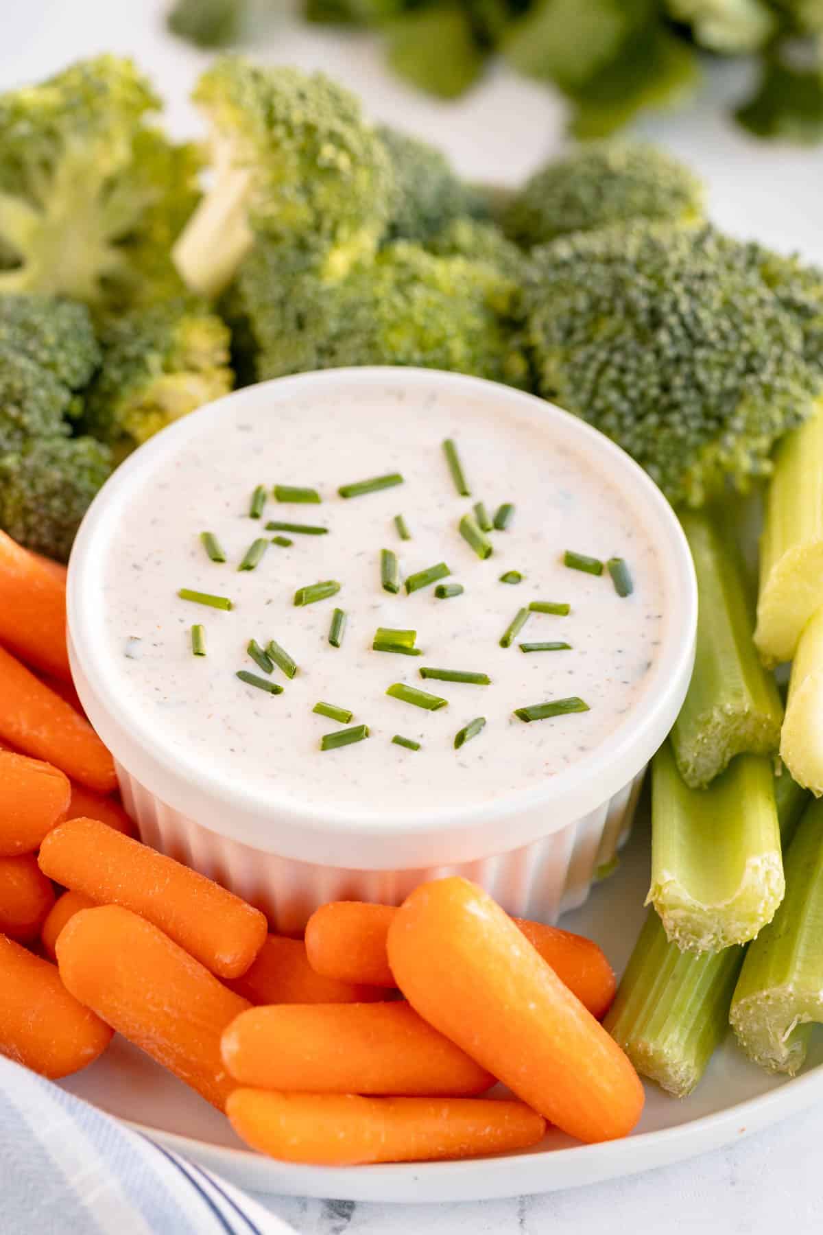 bowl of ranch dressing surrounded by veggies.