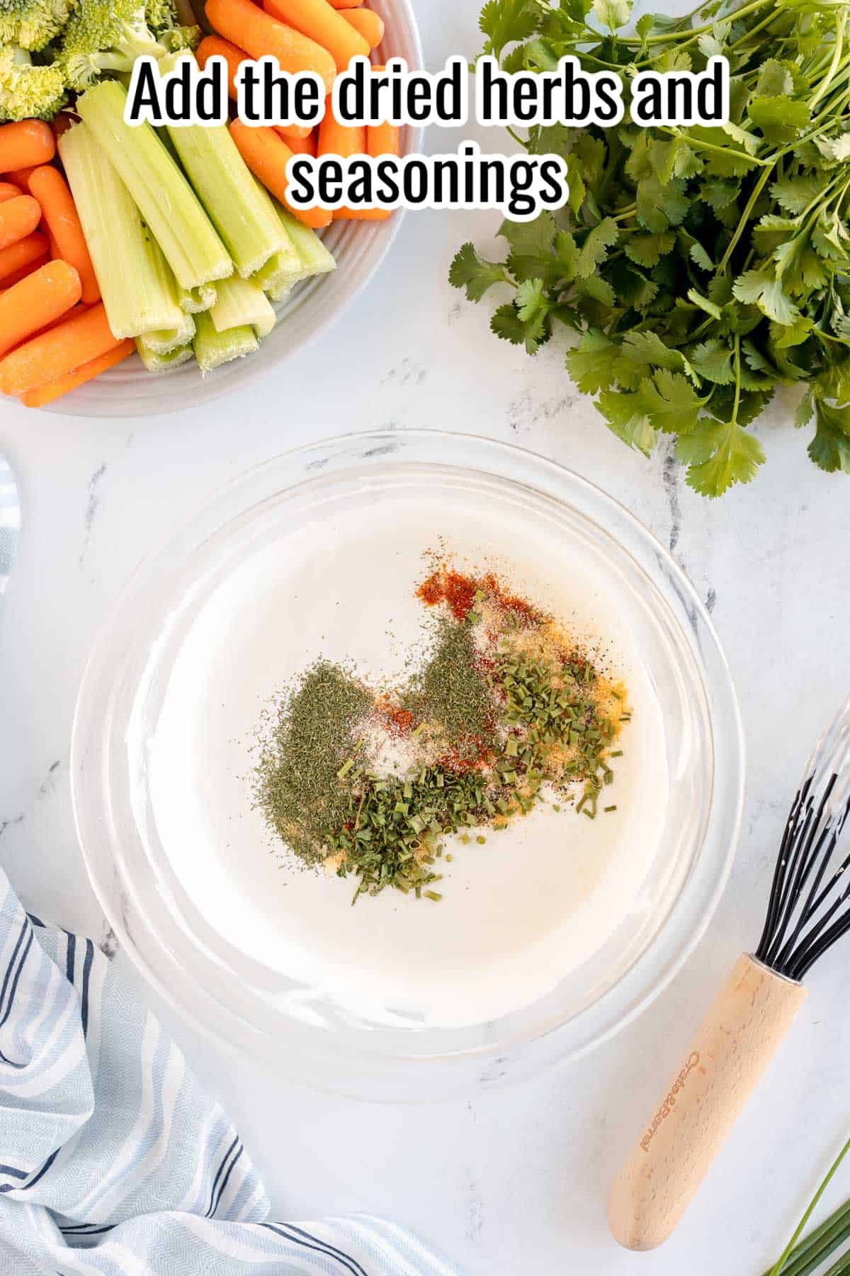 a bowl of homemade ranch dip with a whisk and fresh veggies.