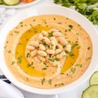 white bean hummus in a bowl with white beans scattered over the top.
