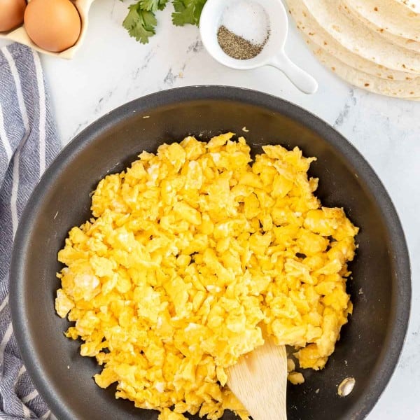 skillet with scrambled eggs and a wooden spoon.