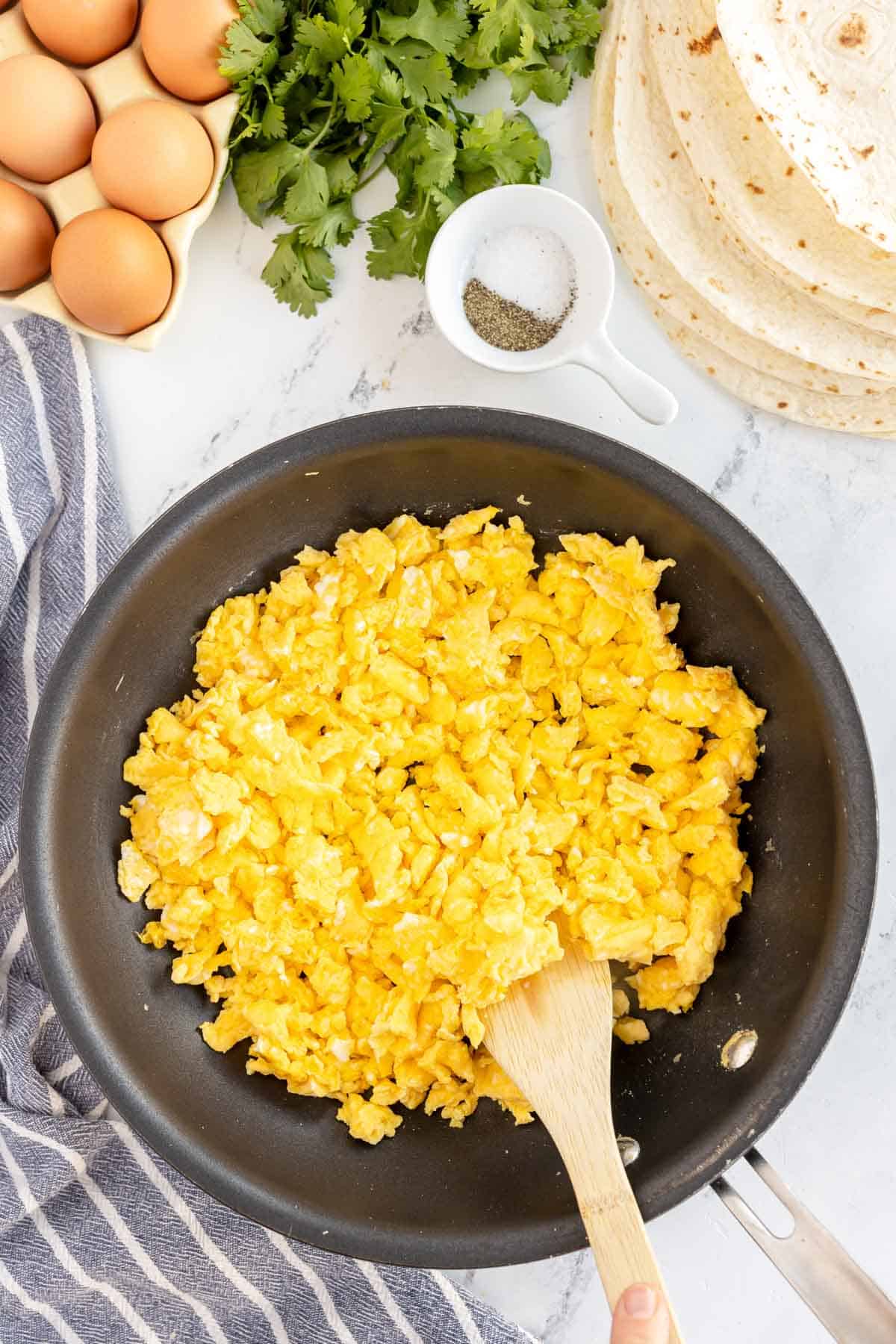 skillet with scrambled eggs and a wooden spoon.