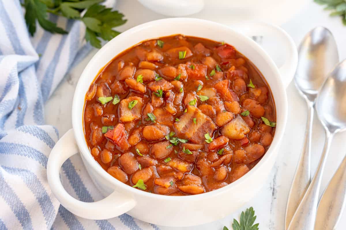 baked beans in a white bowl with a blue striped napkin.