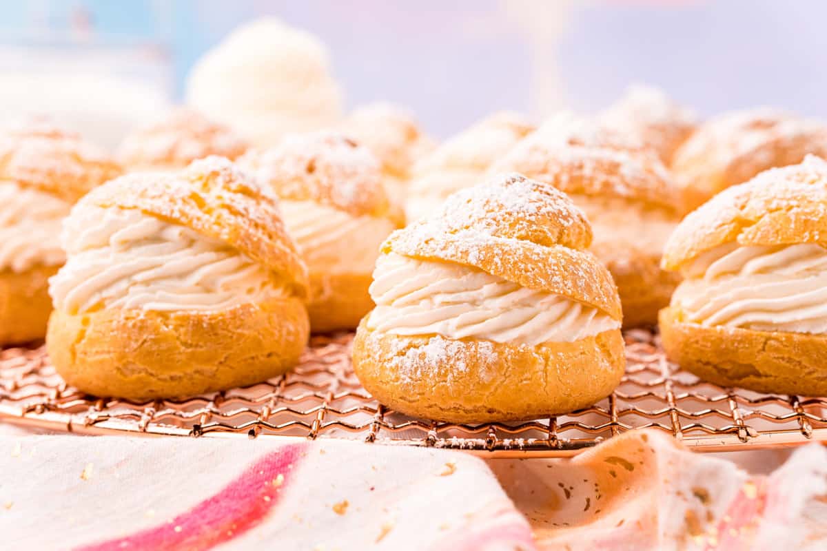 cream puffs filled with whipped cream on a wire rack.