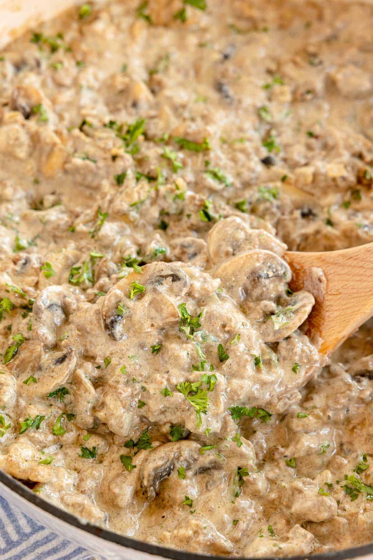 ground beef stroganoff in a skillet with a wooden spoon.