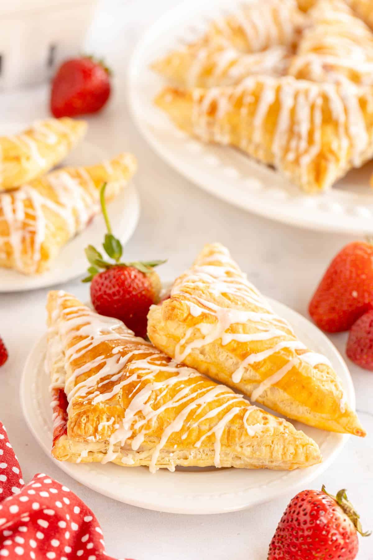 A plate of strawberry turnovers with icing on top.