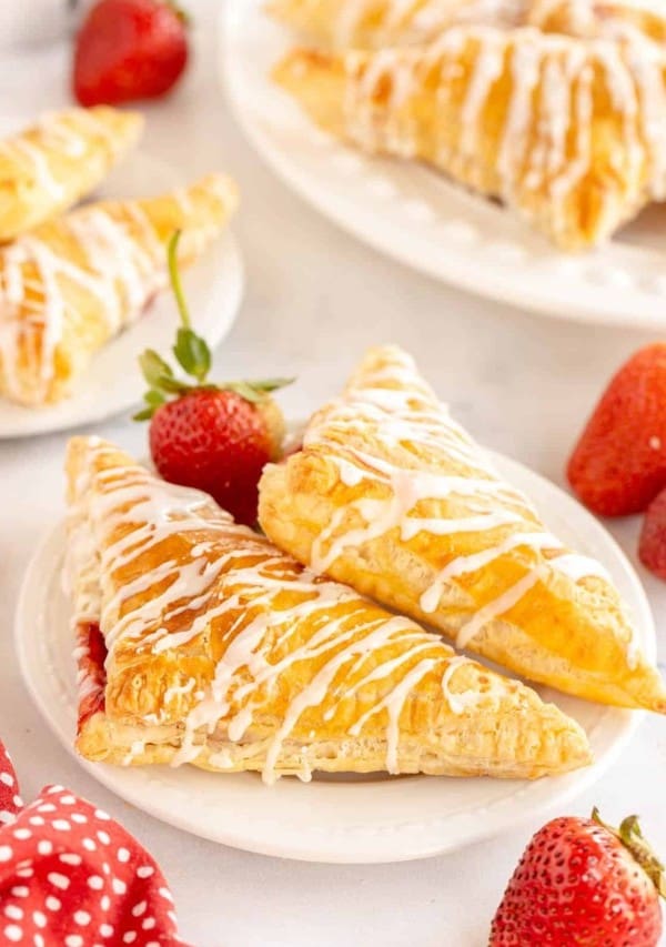 A plate of strawberry turnovers with icing on top.