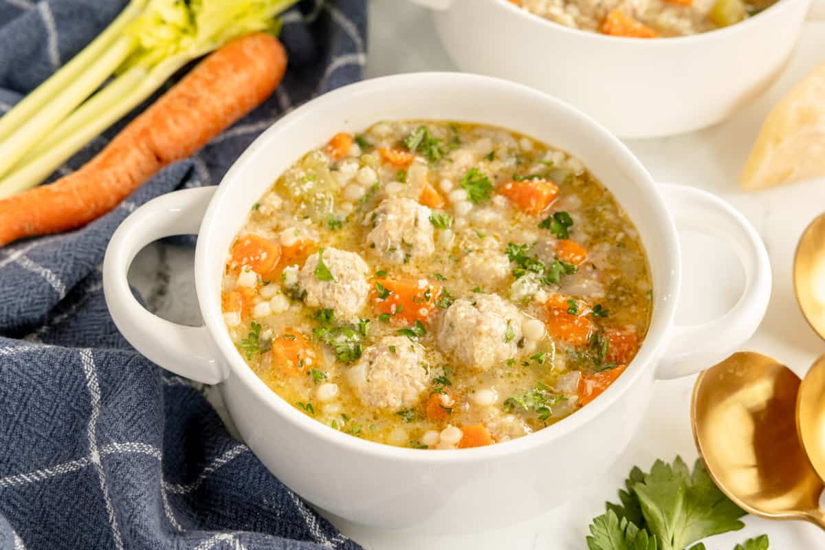 A bowl of meatball soup with carrots and celery.
