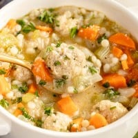 A bowl of soup with meatballs and carrots.