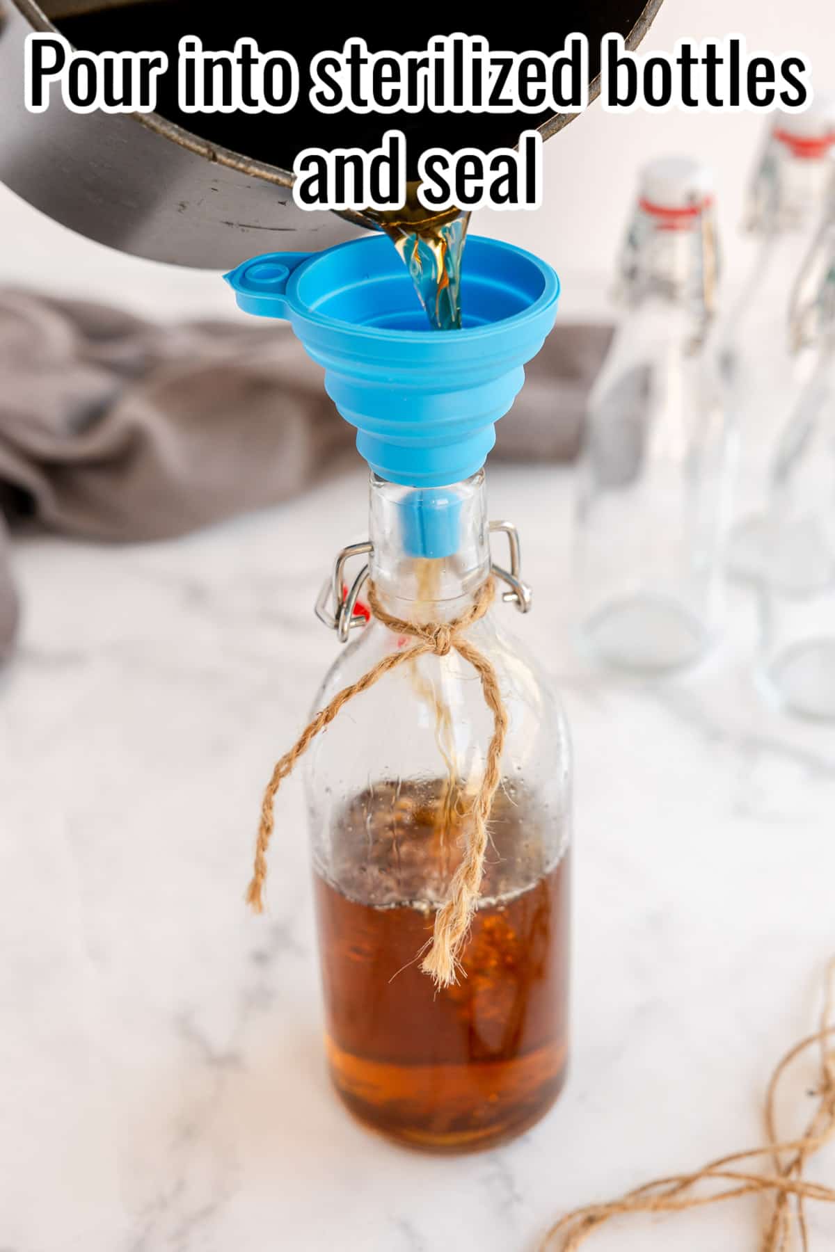 process image showing homemade amaretto being poured into a glass bottle with a funnel.