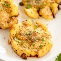 close up of smashed potatoes on a white plate