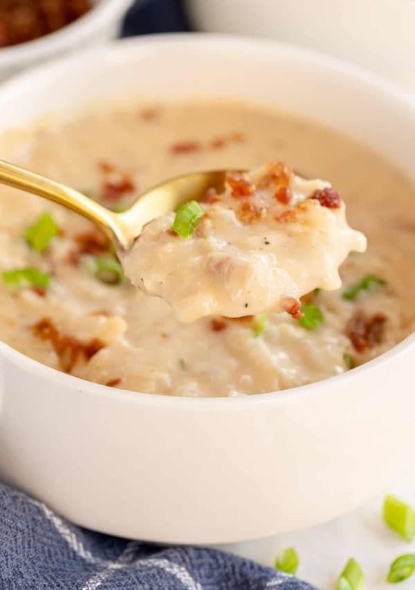 potato cheese soup on a spoon, with a white bowl.